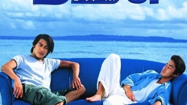 Zwei Männer entspannen auf einem blauen Sofa im Wasser, im Hintergrund der Titel „Beach Boys“.
