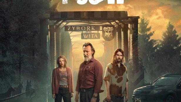 Das Filmplakat für „Wzgórze Psów“ zeigt drei Personen vor einem Ortseingangsschild.