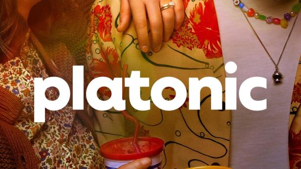 Das Filmplakat für „Platonic“ zeigt zwei Freunde, die eng beieinander stehen und Getränke halten.