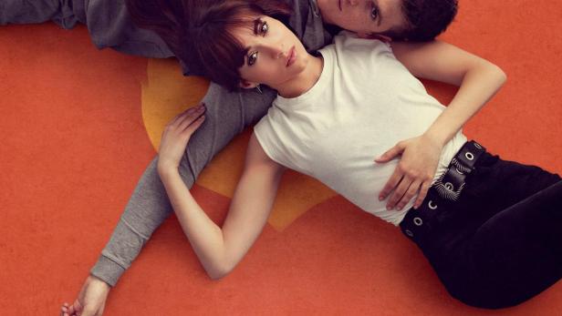 Ein Mann und eine Frau liegen auf einem orangefarbenen Hintergrund, darüber der Titel „La Última“.