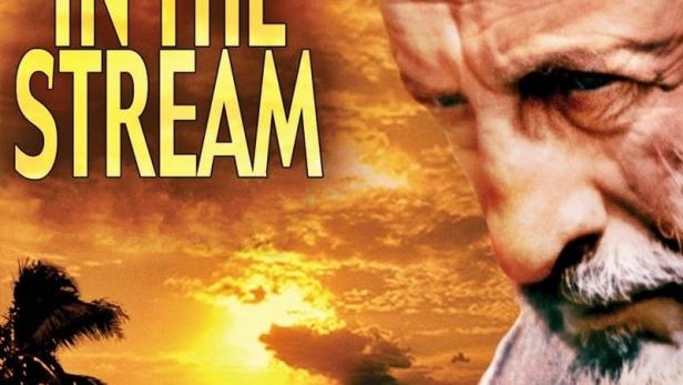 Das Filmplakat für „Inseln im Strom“ zeigt einen Mann vor einer tropischen Insellandschaft bei Sonnenuntergang.