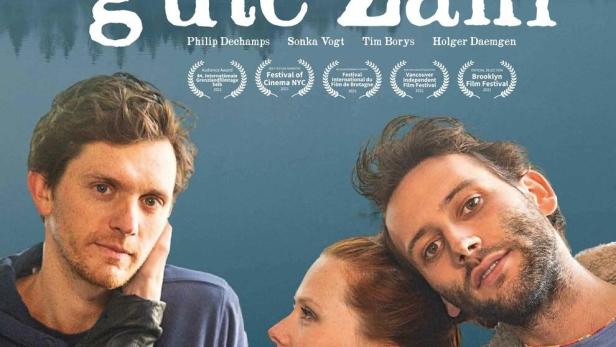 Das Filmplakat zu „Zwei ist eine gute Zahl“ zeigt drei Schauspieler vor einem See.
