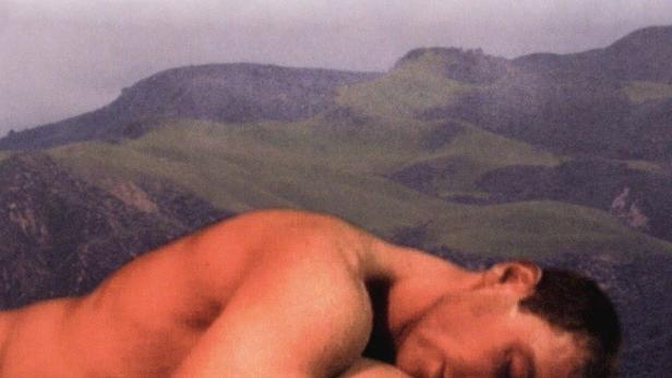 Das Filmplakat für „Gone, But Not Forgotten“ zeigt zwei Männer, die sich vor einer Hügellandschaft umarmen.