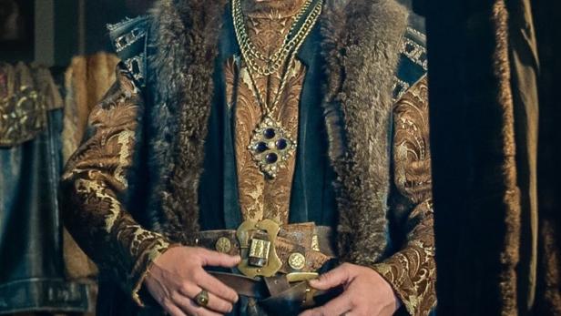 Ein Mann mit Krone und prächtigen Gewändern posiert für ein historisches Drama.