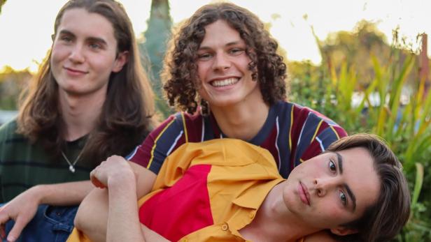 Drei junge Männer posieren im Freien für ein Foto.