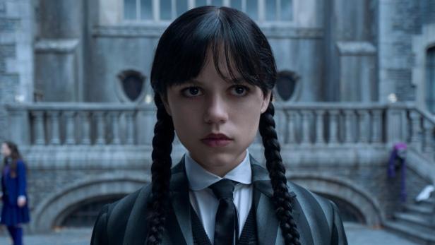 Jenna Ortega als Wednesday Addams vor dem Nevermore Academy Gebäude.