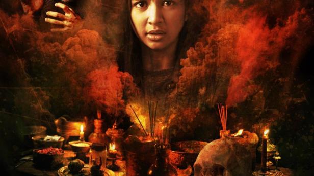 Das Filmplakat für „Teluh Darah“ zeigt eine verängstigte Frau und rituelle Gegenstände wie einen Schädel.