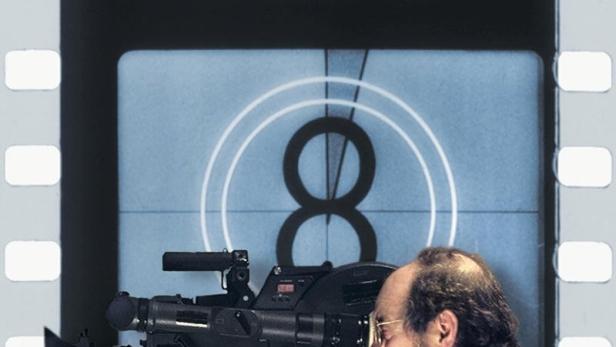 Ein Mann hinter einer Filmkamera vor dem Hintergrund des Filmplakats „Stanley Kubrick: A Life in Pictures“.