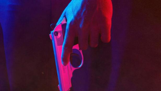 Ein Mann hält eine Pistole vor dem Hintergrund des Titels „Curse of the Chippendales“.