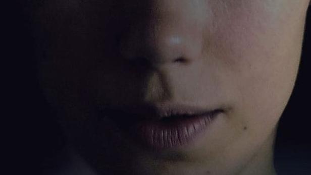 Das Filmplakat für „Outlier“ zeigt das Gesicht einer jungen Frau über einer Landschaft.