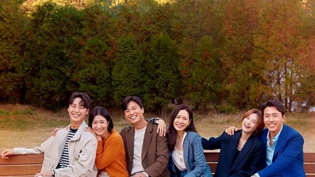 Sechs Schauspieler sitzen auf einer Bank vor Bäumen für das Werbeplakat von „Thirty-Nine“.