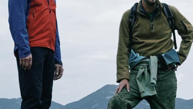 Zwei Männer stehen vor einer Bergkulisse, vermutlich eine Szene aus dem Film „Riesending: Jede Stunde zählt“.