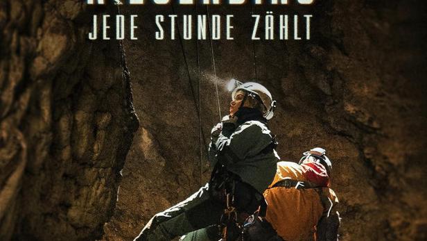 Ein Höhlenforscher seilt sich mit einer verletzten Person in einer dunklen Höhle ab.