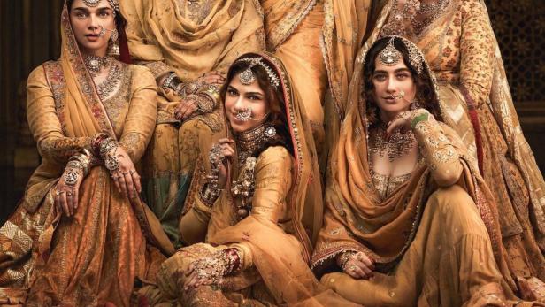 Sechs Frauen in traditioneller Kleidung posieren für ein Werbeplakat von „Heeramandi: The Diamond Bazaar“.