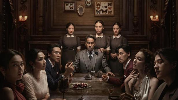 Das Filmplakat zeigt eine Gruppe von Menschen, die an einem Tisch in einem opulenten Raum sitzen.