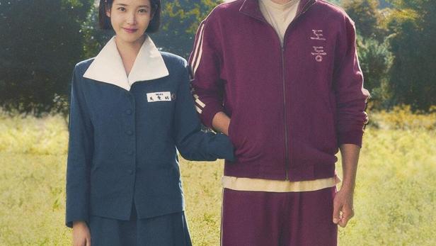 Ein Mann und eine Frau in Schuluniform stehen in einem Feld mit Blumen.