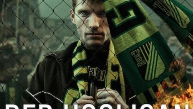 Ein Mann mit einem Schal steht vor einem Zaun, im Hintergrund das Logo von Netflix und der Titel „Der Hooligan“.
