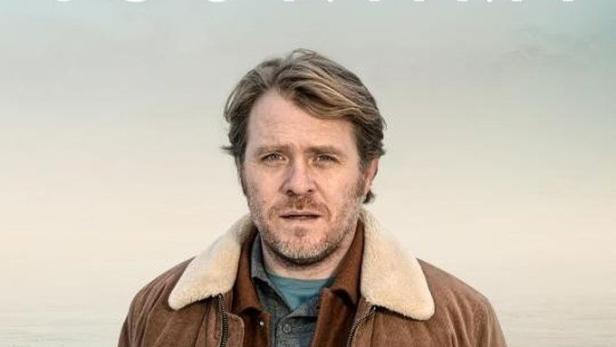 Ein Mann in einer braunen Jacke vor dem Filmtitel „Tsunami“ und silhouettierten Figuren.