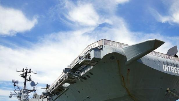 Das Flugzeugträgerschiff „Intrepid“ unter blauem Himmel mit weißen Wolken.