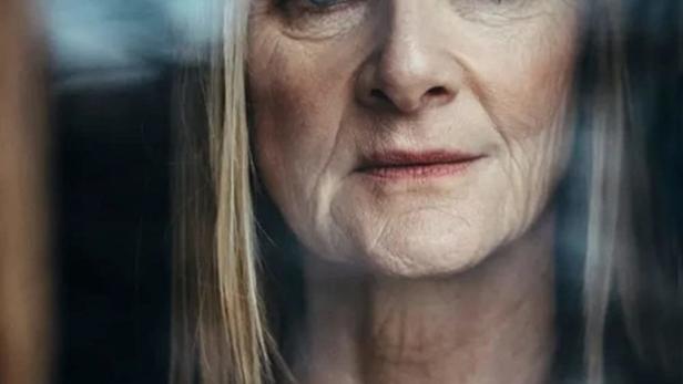 Das Gesicht einer älteren Frau vor dem Titelbild von „Before We Die“.