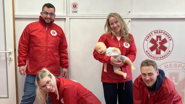Vier Personen in roter „First Responder Niederösterreich“-Jacke üben Wiederbelebung an Puppen.