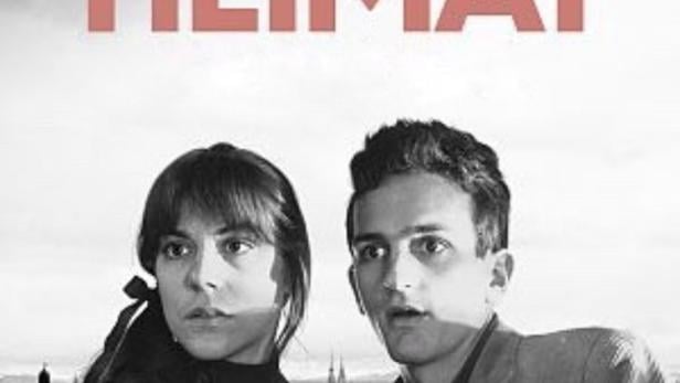 Das Filmplakat für „Die zweite Heimat“ zeigt ein junges Paar vor einer Stadtkulisse.