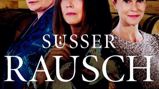 Drei Frauen stehen vor einem Hintergrund aus Weinfässern, im Vordergrund der Titel „Süsser Rausch“.