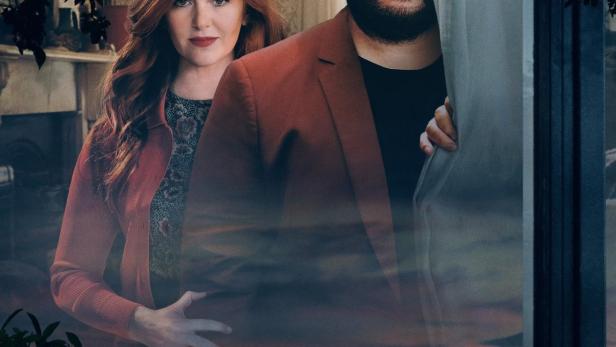 Das Filmplakat für „Wolf Like Me“ zeigt Isla Fisher und Josh Gad durch ein Fenster.