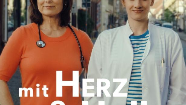 Zwei Ärztinnen stehen vor einer Stadtkulisse, beworben als „mit Herz & Holly“.