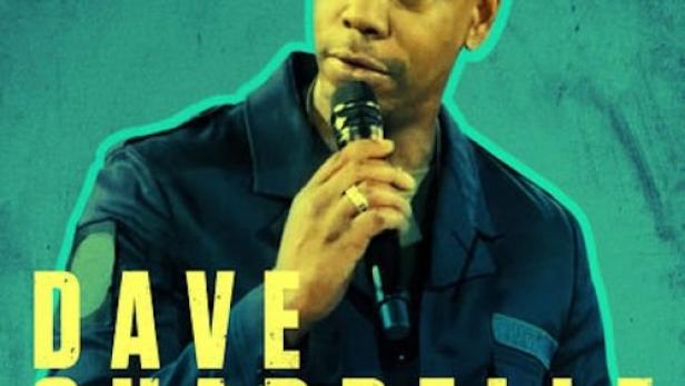 Der Comedian Dave Chappelle hält ein Mikrofon in der Hand.