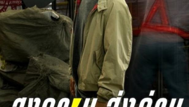 Ein Mann steht vor einem Förderband mit Paketen in einer Lagerhalle.