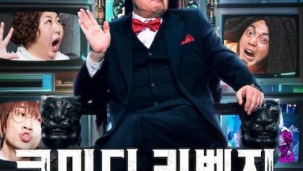 Ein Mann im Anzug sitzt auf einem Thron, umgeben von Fernsehern mit komischen Gesichtern.