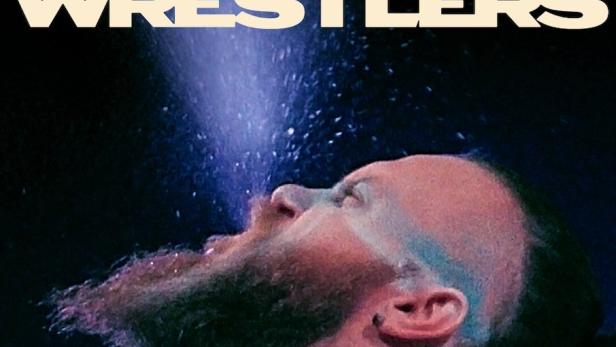 Ein Mann mit Bart blickt auf dem Filmplakat zu „Wrestlers“ in einen Lichtstrahl.