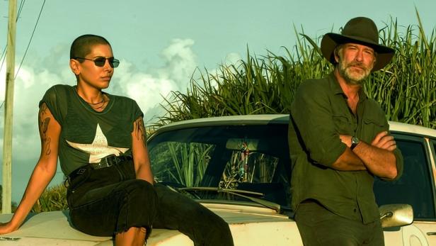 Zwei Schauspieler posieren vor einem alten Auto für die Serie „Troppo“.