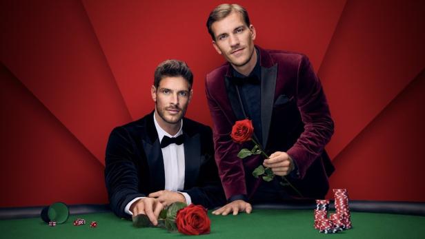 Martin und Felix, die „Machelors“, posieren mit Rosen an einem Spieltisch.