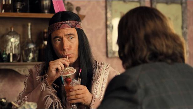 Ein Mann im Kostüm trinkt einen Cocktail mit Erdbeere.