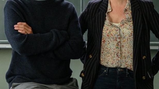 Zwei Lehrer stehen vor einer Tafel mit mathematischen Formeln.