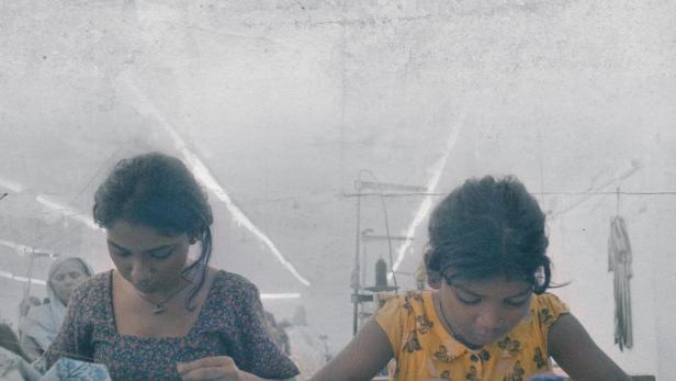 Zwei junge Frauen arbeiten in einer Fabrik an Textilien.