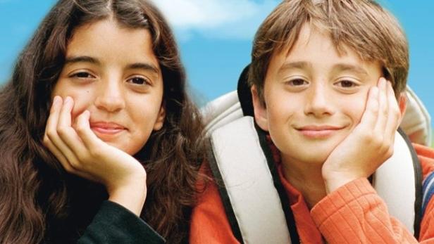 Das Filmplakat für „2 Kleine Helden“ zeigt zwei Kinder im Gras liegend.