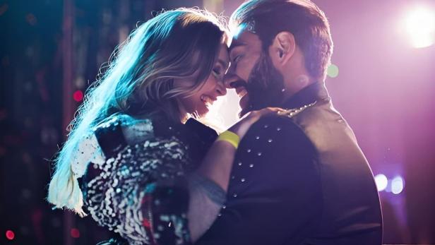 Ein Paar tanzt eng umschlungen vor dem Schriftzug „Rodeio Rock“.