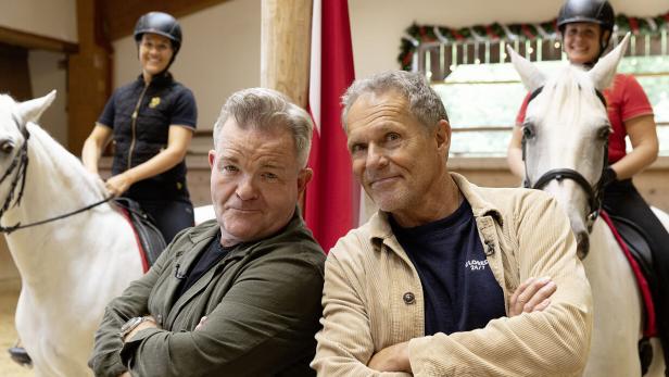 Zwei Männer posieren vor zwei Frauen, die auf weißen Pferden reiten.