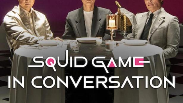 Drei Männer sitzen an einem Tisch im Stil von „Squid Game“ für ein Gespräch.