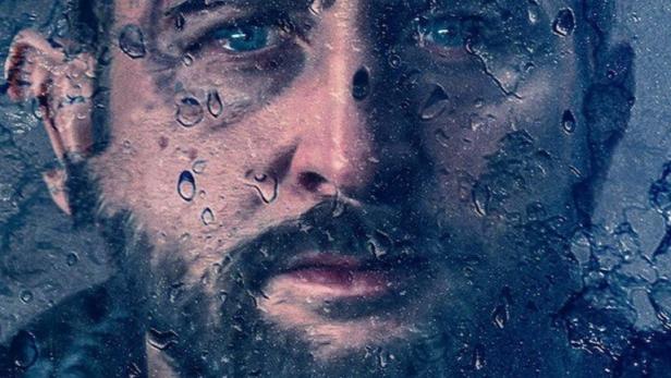 Ein Porträt von einem Mann mit Bart, gesehen durch eine regennasse Scheibe, mit dem Wort „Forst“ im Vordergrund.