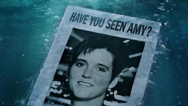 Ein Poster mit der Aufschrift „Have you seen Amy?“ treibt im Meer, im Hintergrund ein Kreuzfahrtschiff.