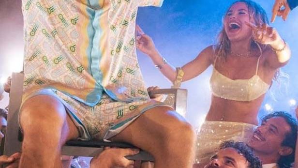 Eine ausgelassene Party mit jungen Leuten und dem Schriftzug „Young Millionaires“.