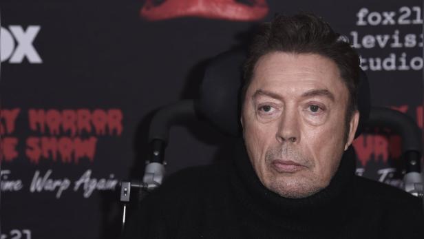 Ein Porträt von Tim Curry vor einem Hintergrund von „The Rocky Horror Picture Show“.