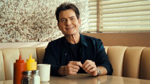 Charlie Sheen sitzt an einem Tisch in einem Restaurant.