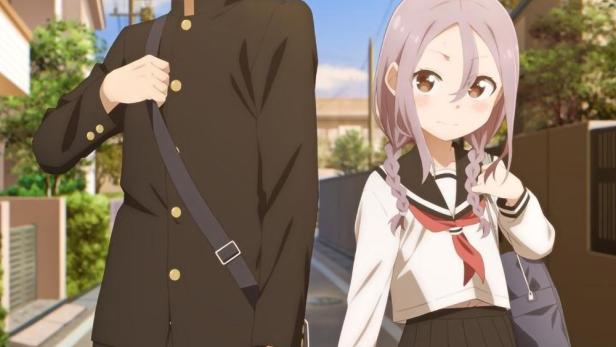 Ein junger Mann und ein junges Mädchen in Schuluniformen gehen eine Straße entlang.