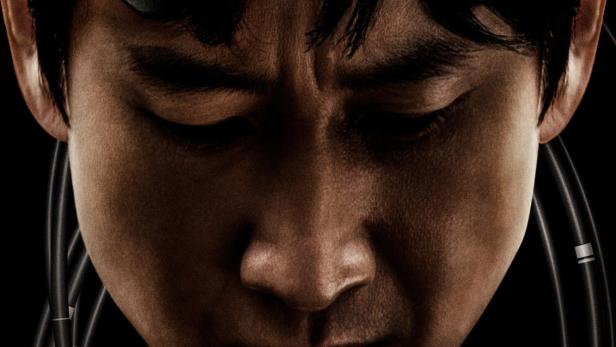 Ein Mann trägt eine futuristische Kopfbedeckung mit Kabeln im Gesicht.