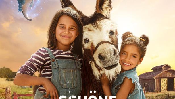 Zwei Mädchen stehen mit einem Esel und zwei kleinen Drachen vor einer Scheune auf der „Schöne Kleine Farm“.